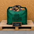 Green bag of firewood labeled 'North Shore Firewood' on a wooden pallet with a 'Oak' sign.