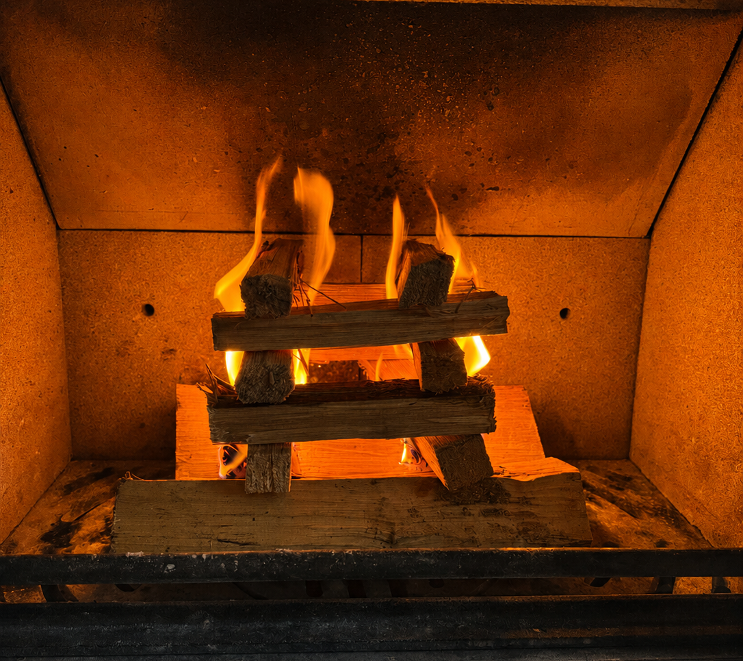 Fireplace with burning logs and flames inside a dark room