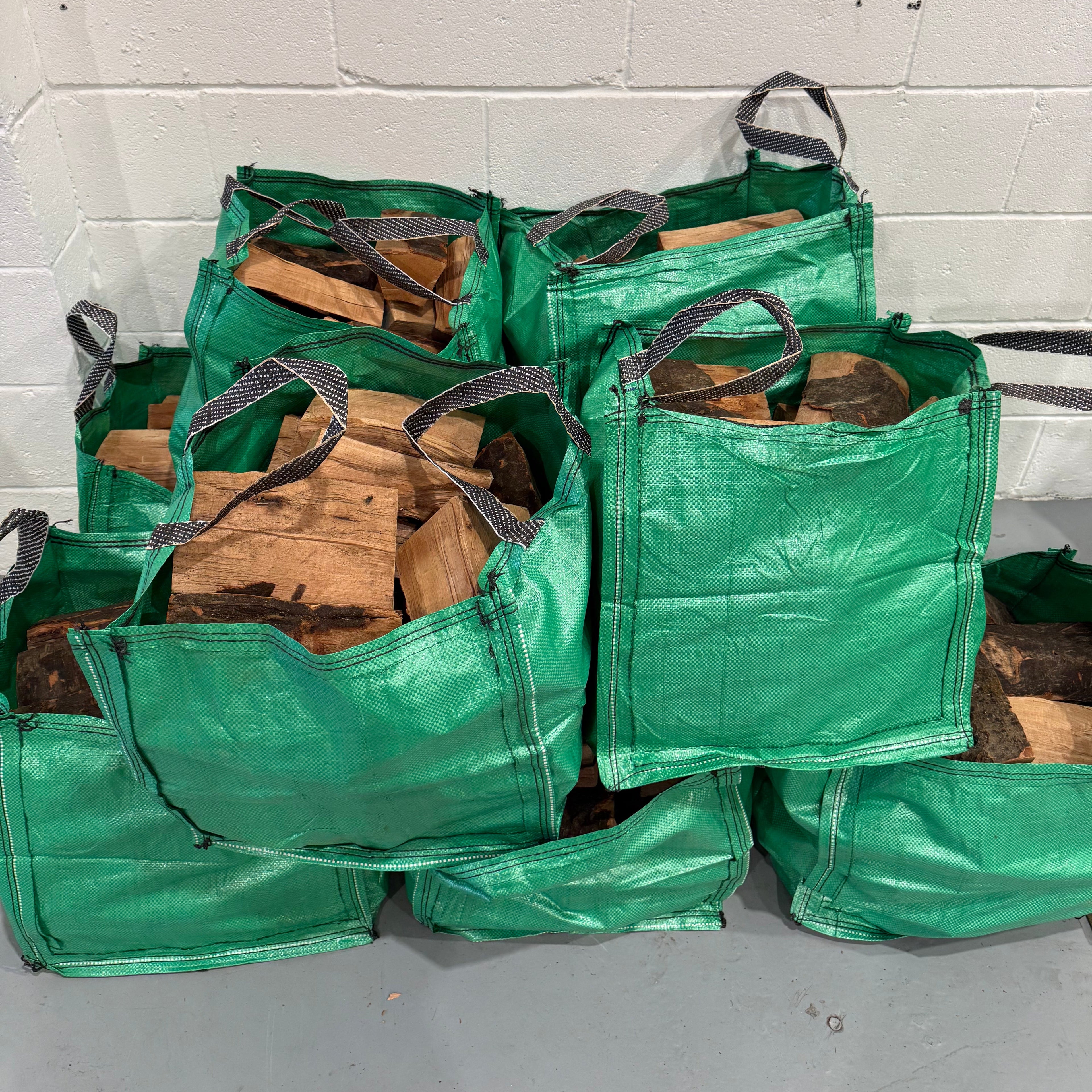 Green Beech firewood storage bag filled with wood against a white wall