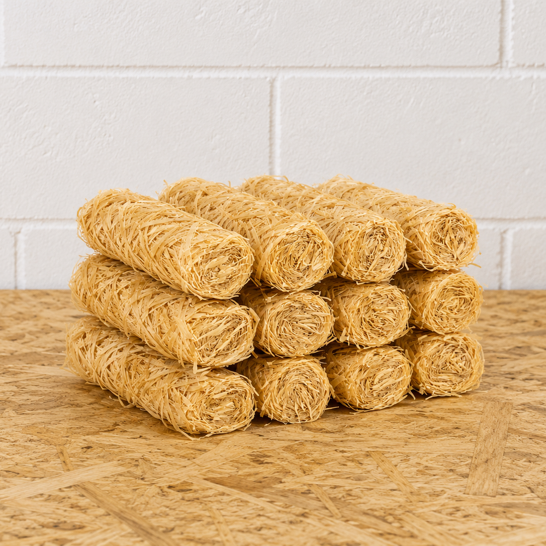 Stack of yellow rolled towels on a wooden surface with a white tiled wall background