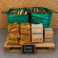 Wooden pallet with bags of wood, kindling packages, and a sign labeled 'Ember Bundle' against a wooden background.